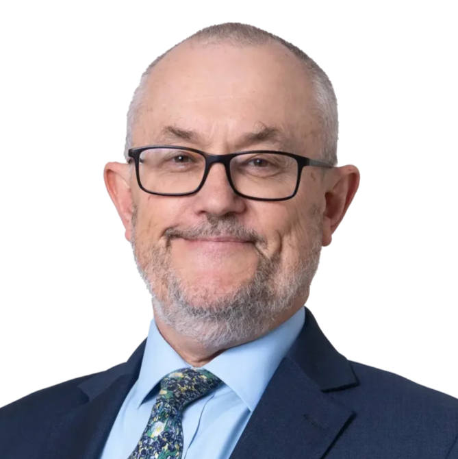 Picture of Michael, he is wearing glasses, a blue shirt with patterned tie, and a black suit jacket.